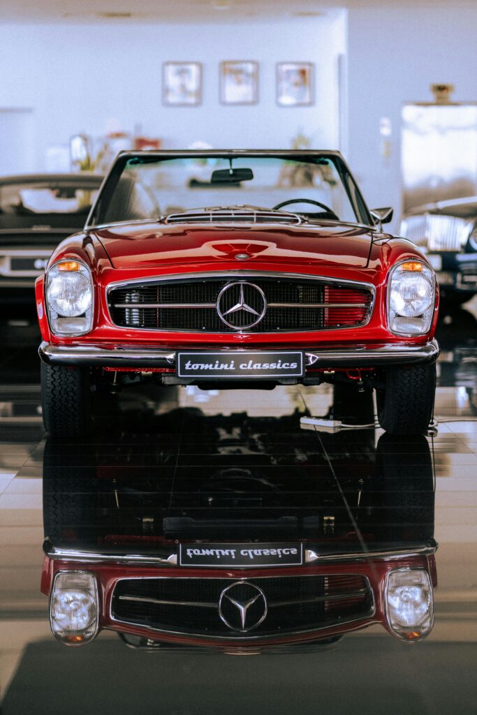 pexels-photo-18434045-18434045 Classic red Mercedes Benz convertible on display in a showroom, perfectly reflected on the polished floor.